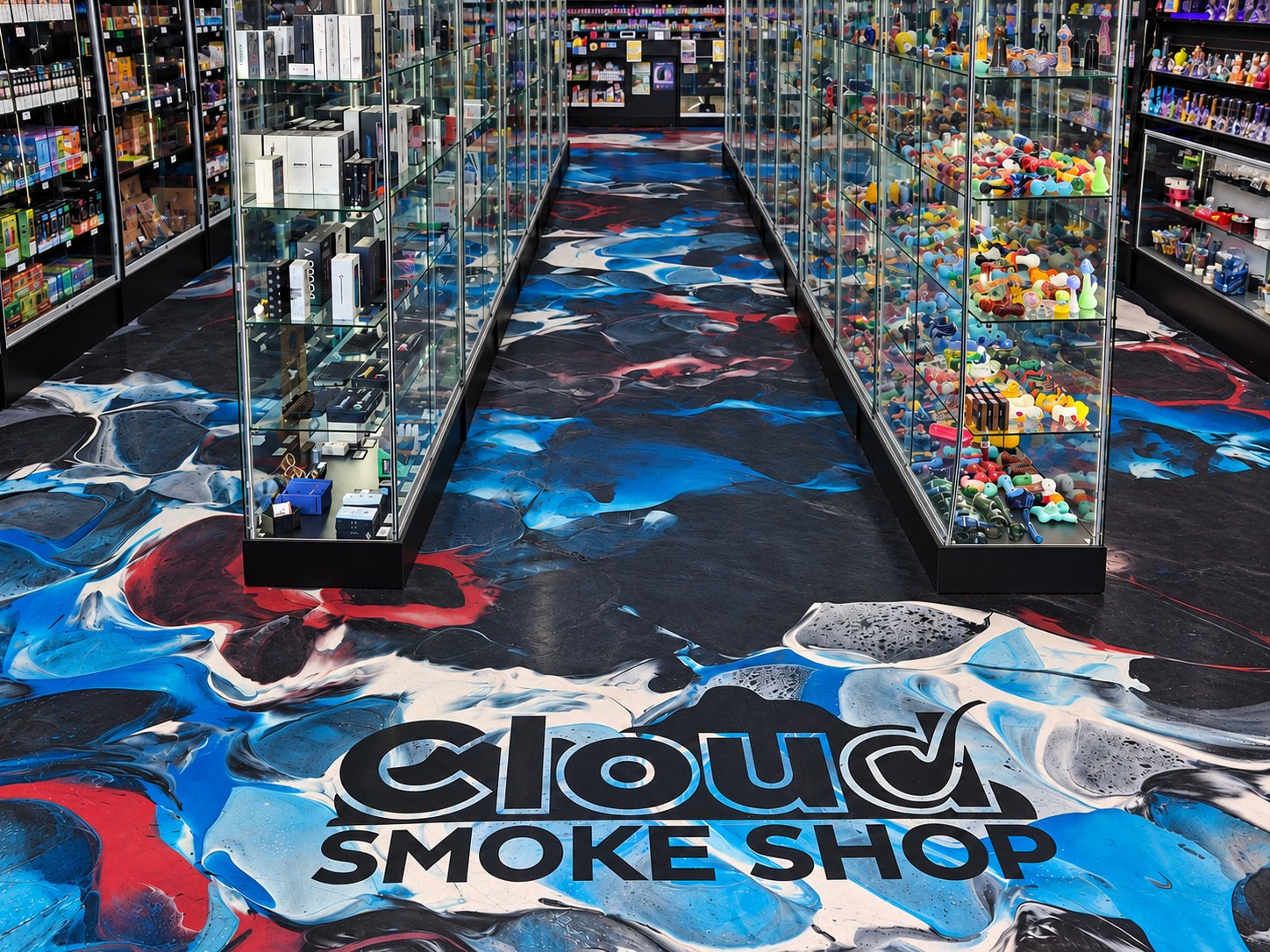 The two aisles at Tennessee Street with the Cloud Smoke Shop logo in the floor between the glass cases